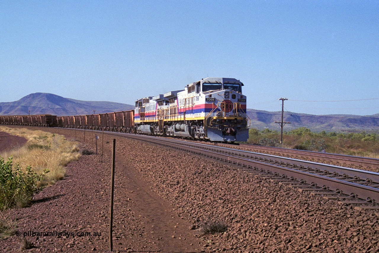 250-14
Pelican Siding on the Hamersley Iron Tom Price line about the 208 km with an empty train behind the standard pairing of two General Electric built 9-44CW units 7068 serial 47747 and 7067 serial 47746 stand on the loop or passing track for a meet with a loaded train. 1550 hrs 21st October 2000.
Keywords: 7068;GE;Dash-9-44CW;47747;