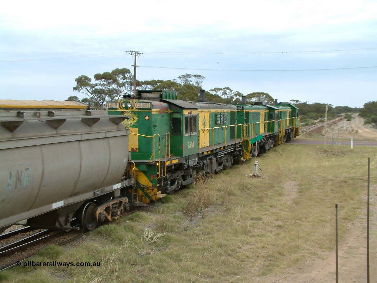 030407 100506
Minnipa, north bound empty grain train shunts across the grade crossing for Minnipa - Yardea Rd behind a trio of former Australian National Co-Co locomotives with rebuilt former AE Goodwin ALCo model DL531 830 class ex 839, serial no. 83730, rebuilt by Port Augusta Workshops to DA class, leading two AE Goodwin ALCo model DL531 830 class units 842, serial no. 84140 and 851 serial no. 84137, 851 having been on the Eyre Peninsula since delivered in 1962, to shunt off empty waggons into the grain siding. 7th April, 2003.
Keywords: 830-class;851;84137;AE-Goodwin;ALCo;DL531;