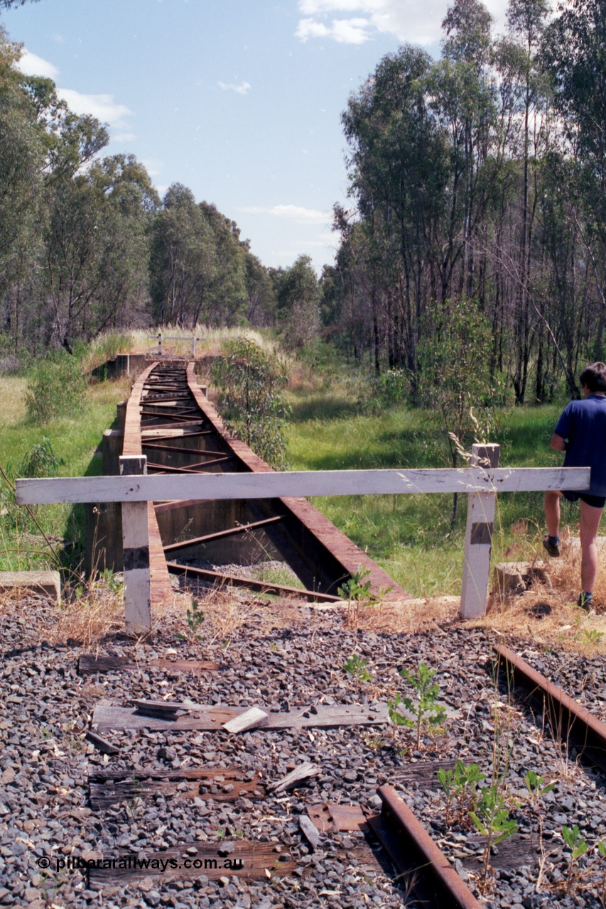118-13
Tocumwal line, looking south from the 15 km/h speed sign, bridge with deck and rail removed, line disconnected and out of service. [url=https://goo.gl/maps/Tgtv4ysFESAbYFWM8]Geo data[/url].
