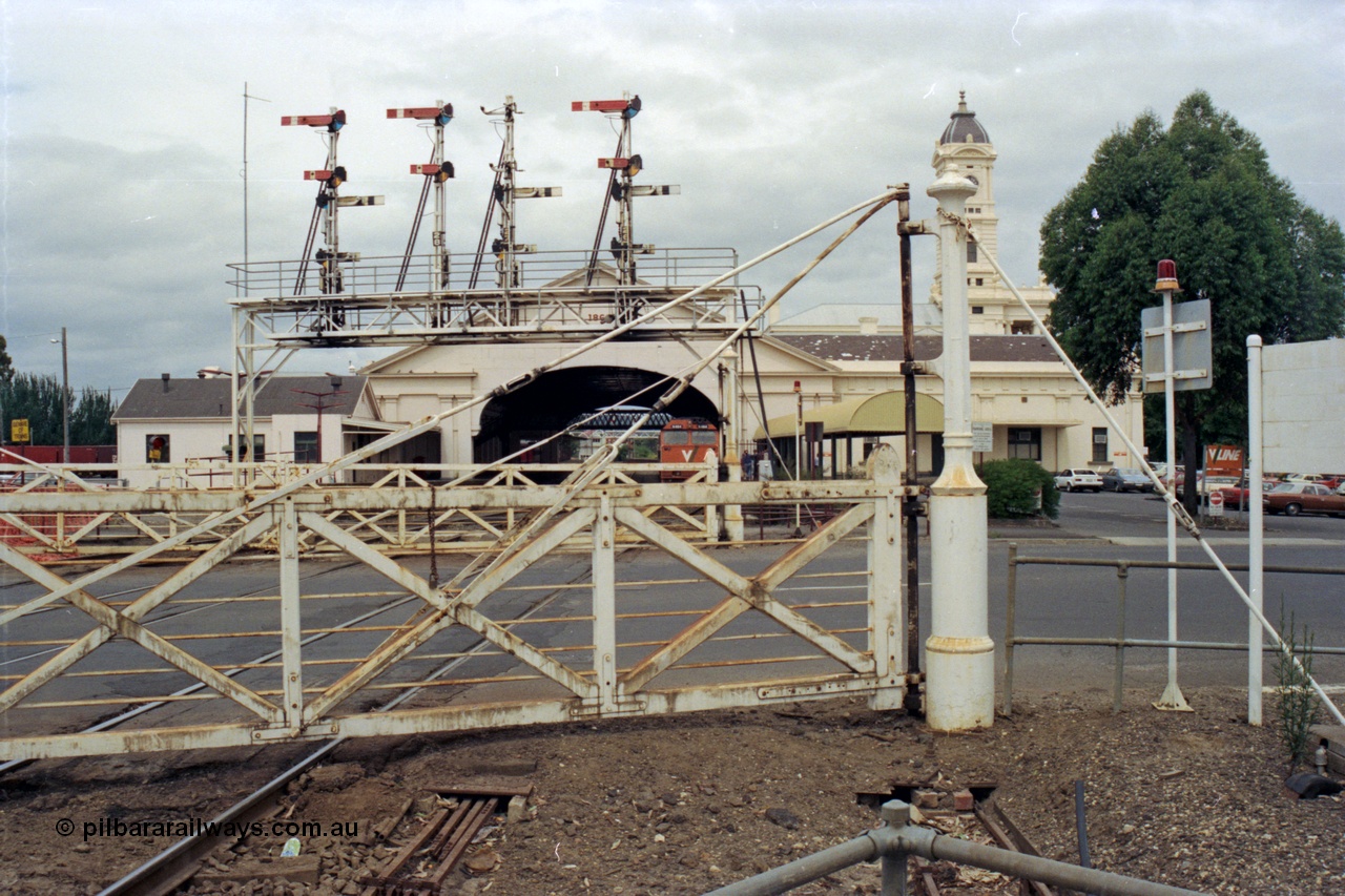 128-13
Ballarat Station, Lydiard St or B signal box, view across Lydiard Street grade crossing, interlocked gates, signal gantry with semaphore signal posts 26 to 29, looking east, V/Line N class N 464 'City of Geelong' Clyde Engineering EMD model JT22HC-2 serial 86-1193 at station, station building and canopy, point rodding under road.
Keywords: N-class;N464;Clyde-Engineering-Somerton-Victoria;EMD;JT22HC-2;86-1193;