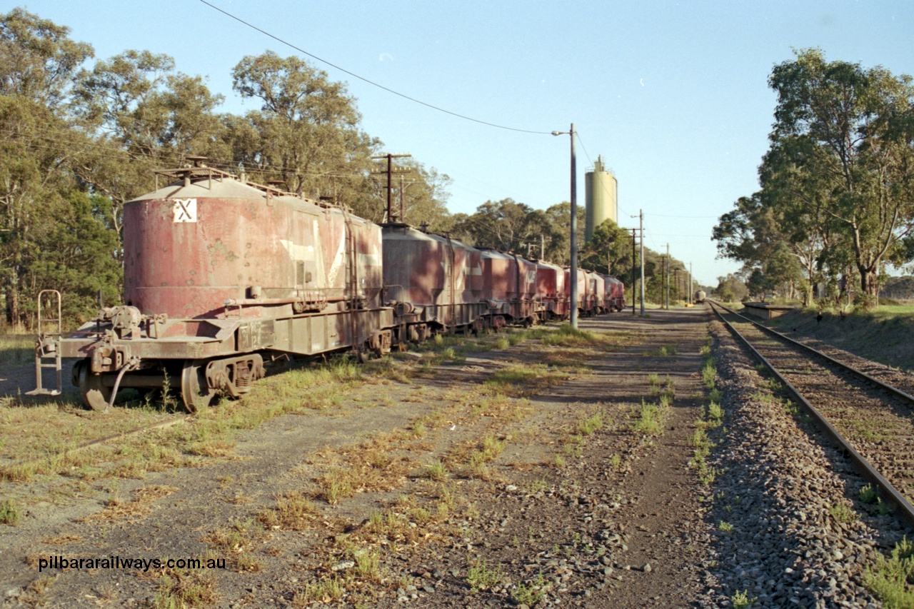 129-1-15
Lyndhurst, station overview, V/Line VPCX type bogie cement waggons in rakes, platform on RHS, looking towards Melbourne, Blue Circle Cement plant in the background. Location is [url=https://goo.gl/maps/4zF5DDSnJN6R9cKe8]Geo Data[/url].
Keywords: VPCX-type;