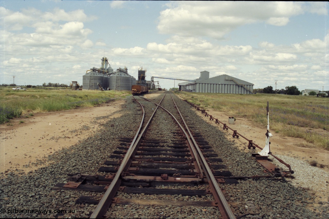 131-1-25
Burraboi station yard overview, looking south from Balranald end, points and derail lever, rice storage complex on the right, new Aquila silo complex on the left, grain waggons.
