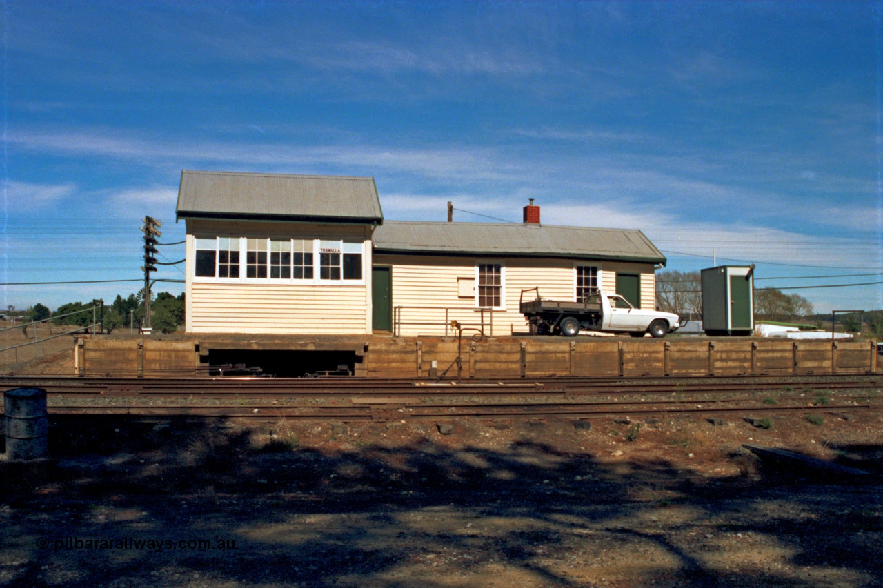 153-2-19
Trawalla station and signal box front elevation from track side, shows signal wires and rodding leaving platform, electric staff auto exchange apparatus set up with staff.
