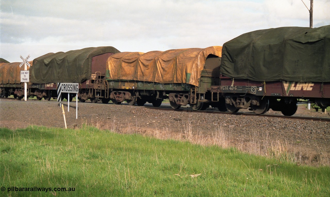 154-13
Lismore, Australian National broad gauge bogie coil steel waggon in the consist of Adelaide bound goods train 9169 crossing Gnarpurt Road sandwich between V/Line VCSX type bogie coil steel waggons VCSX 40 and VCSX 25.
