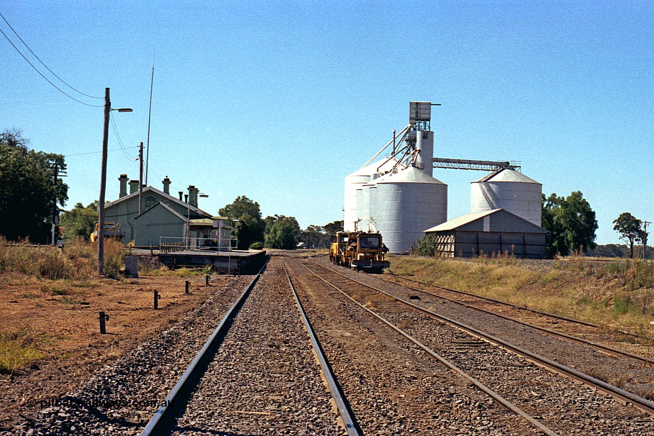 173-21
Murchison East, station yard overview looking north, goods shed and station building and platform, track machines, and horizontal grain bin with Murphy, with steel annex, and Ascom Jumbo style silo complexes.
