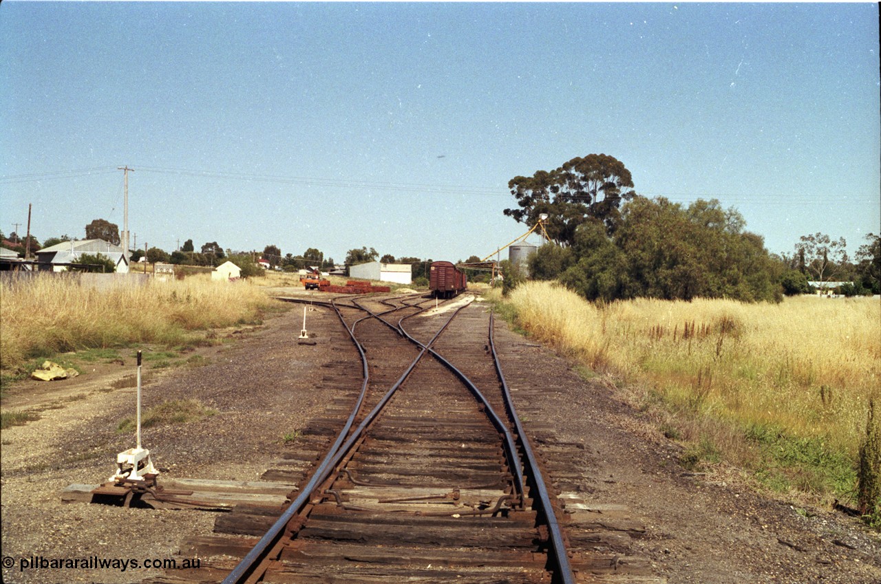 182-04
Wahgunyah, station yard overview looking north along No.1 Road, rake of bogie waggons on No.2 Road with Delarue silo complex on site of former station building, points with hand locking bar, road curving around to the left is for the super phosphate sheds, portable station building and red gum sleeper stockpile in middle frame.
