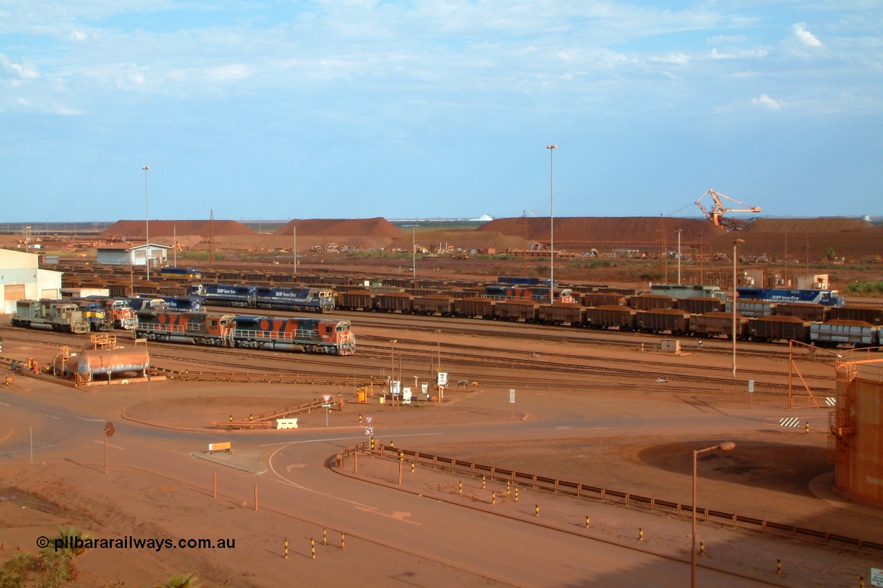 041119 163032r
Nelson Point, how is this for a Parade of Pilbara Power? On the afternoon of Friday the 19th of November 2004 a photo was managed with no less than fourteen locos in the shot, seven at the workshops, and seven on trains at the car dumper roads. Locos in the frame are: 3085, 3080, 3092, 5639, 5636, 5667, 6074 at the workshops and, 6073, 3082, 3079, 5640, 5669, 3078, and 5630 on the car dumper roads. Models are EMD SD40R and SD40-2, GE AC6000 and Goninan GE CM40-8M.
