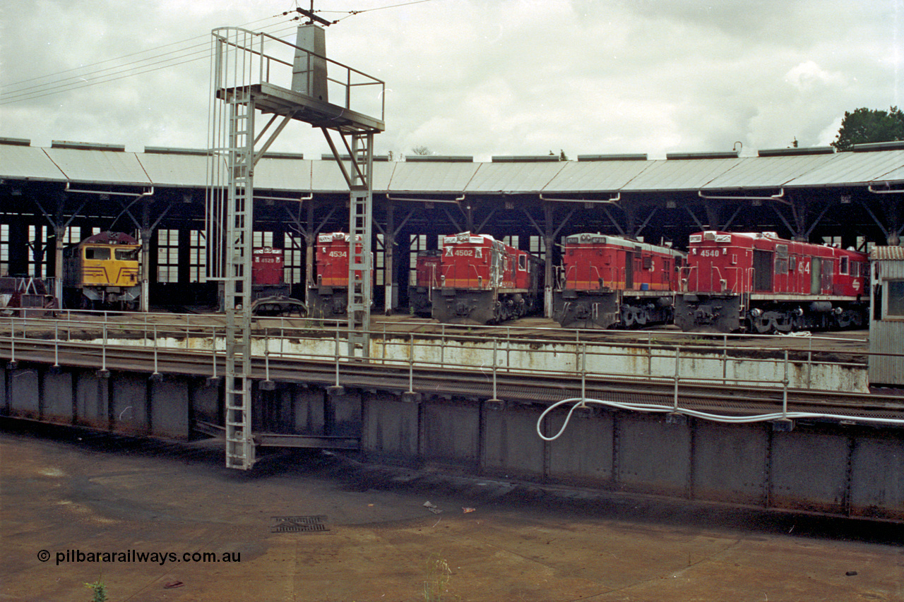 192-06
Junee, NSWSRA standard gauge locomotive depot, view across the turntable at roundhouse stalls 24 to 34 with 80 class ALCo CE615A 8045 in 25, and then ALCo RSD-20/DL-541 45 class units 4529, 4534, 4503, 4502, 4516 and 4540. The 45 class units are in the process of being sealed up for storage.
Keywords: AE-Goodwin;ALCo;Comeng-NSW;RSD-20;DL-541;CE615A;