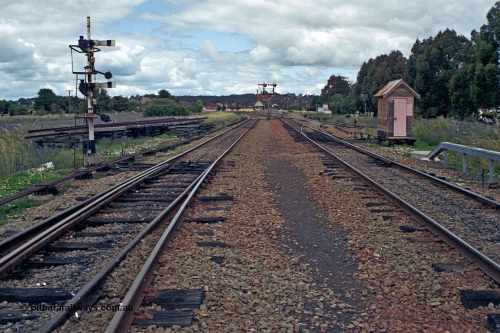 192-30
Cootamundra West, NSW, looking east in the up direction, with the Loop Line on the left and the Temora Main Line in the middle with the points to the right for Tumut Siding with the road running back west on the far right the C.O.R. Siding. The little hut is for Frame D. The signal post on the is for down movements and the arms are operated by levers 29 and 30 and are for down moves from the Loop Line to either Temora Main Line or Refuge and Goods Sidings. The Up Main Line and South Fork semaphores can be seen in the distance.

