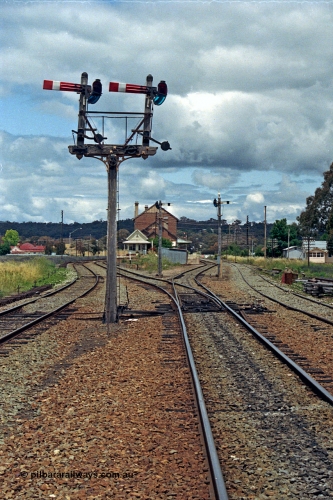 192-31
Cootamundra West, NSW, looking east in the up direction with the Loop Line on the left, Main Line lower quadrant semaphores for up movements to Main Line operated by lever 41 and South Fork to the right from lever 46, with each respective lines down semaphore signals facing away. The signal box and station are in the distance and the siding at right is the Tumut Siding. The house in the distance looks a lot like a NSWGR departmental residence.
