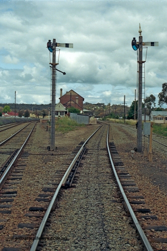 192-32
Cootamundra West, NSW, looking east in the up direction with the Loop Line on the far left, Main Line lower quadrant semaphore for down movements to Main Line operated by lever 7 and South Fork down movements to Main Line by lever 3, the point clearance bars are visible, the signal box and station along with the Ganger's trolley hut are in the distance and the siding at right is Tumut Siding. The house in the distance looks a lot like a NSWGR departmental residence.
