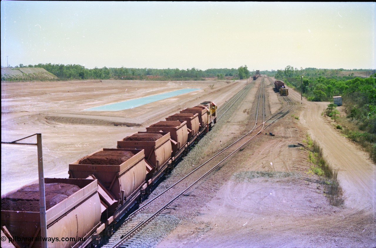 212-14
Weipa, a loaded train ex-Andoom Mine runs along the main with thirty two waggons at Lorim Point towards the dump station behind Comalco R 1004 Clyde Engineering EMD JT26C serial 90-1277 which is former Goldsworthy Mining loco GML 10.
