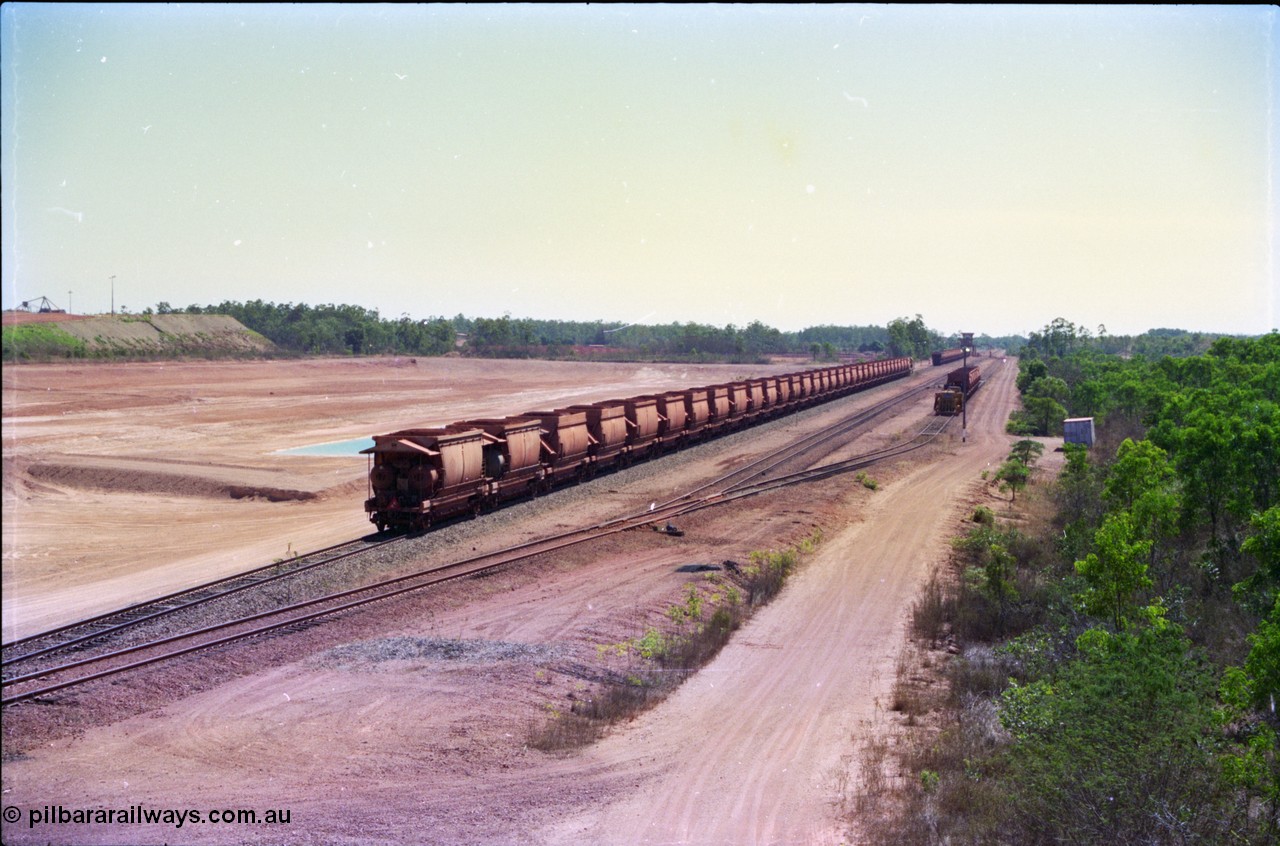 212-15
Weipa, a loaded train ex-Andoom Mine runs along the main with thirty two waggons at Lorim Point towards the dump station behind Comalco R 1004 Clyde Engineering EMD JT26C serial 90-1277 which is former Goldsworthy Mining loco GML 10.
