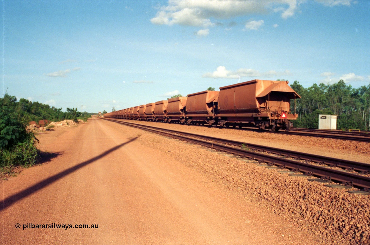 213-07
Weipa, Lorim Point, view looking east from the workshops towards the dump station with a rake of waggons lined up with the two types of aluminium bottom discharge hoppers discernible by the hungry boards fitted to the original type waggons, the control cabin for the dump station can be made out in the distance.
