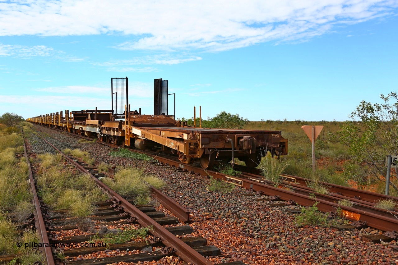 180614 1329
Allen Siding, at the 45 km looking east, the original rail or steel train is stowed on the mainline, looking from 1st lead off waggon 6011, built by Scotts of Ipswich 04-09-1970, the mesh guarding is for the winch cable. The chute arrangement for the discharging and recovery of rail is visible. 14th June 2018. [url=https://goo.gl/maps/UE2dRkZvdBr]GeoData[/url].
