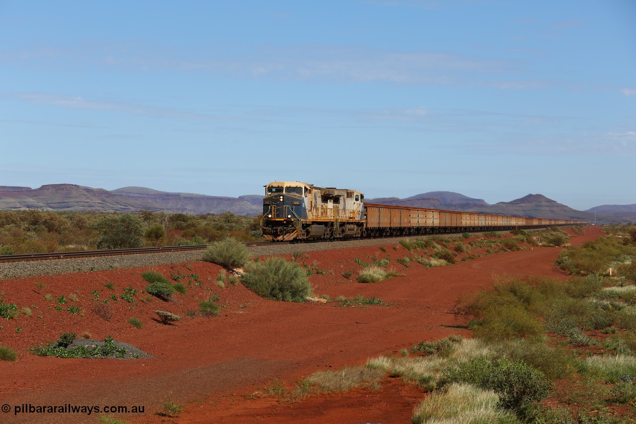 150507 8043
FMG Solomon Line, as the Nanutarra - Wittenoom Road was realigned when this line was built, this is where the western shortcut branch of the Roebourne - Wittenoom Road crosses the line before rejoining the Nanutarra Road. A loaded train behind double General Electric Dash Dash 9-44CW Co-Co locomotives, units 010 serial no. 58187 and 014 serial no. 58191 power a loaded along the straight, there are bank engines on the rear. Geodata: [url=https://goo.gl/maps/upAfsxGcMED2] -22.1617767 118.1279150 [/url].
