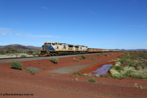 150507 8046
FMG Solomon Line, as the Nanutarra - Wittenoom Road was realigned when this line was built, this is where the western shortcut branch of the Roebourne - Wittenoom Road crosses the line before rejoining the Nanutarra Road. A loaded train behind double General Electric Dash 9-44CW Co-Co locomotives, units 010 serial no. 58187 and 014 serial no. 58191 power a loaded along the straight, there are bank engines on the rear. Geodata: [url=https://goo.gl/maps/upAfsxGcMED2] -22.1617767 118.1279150 [/url].
