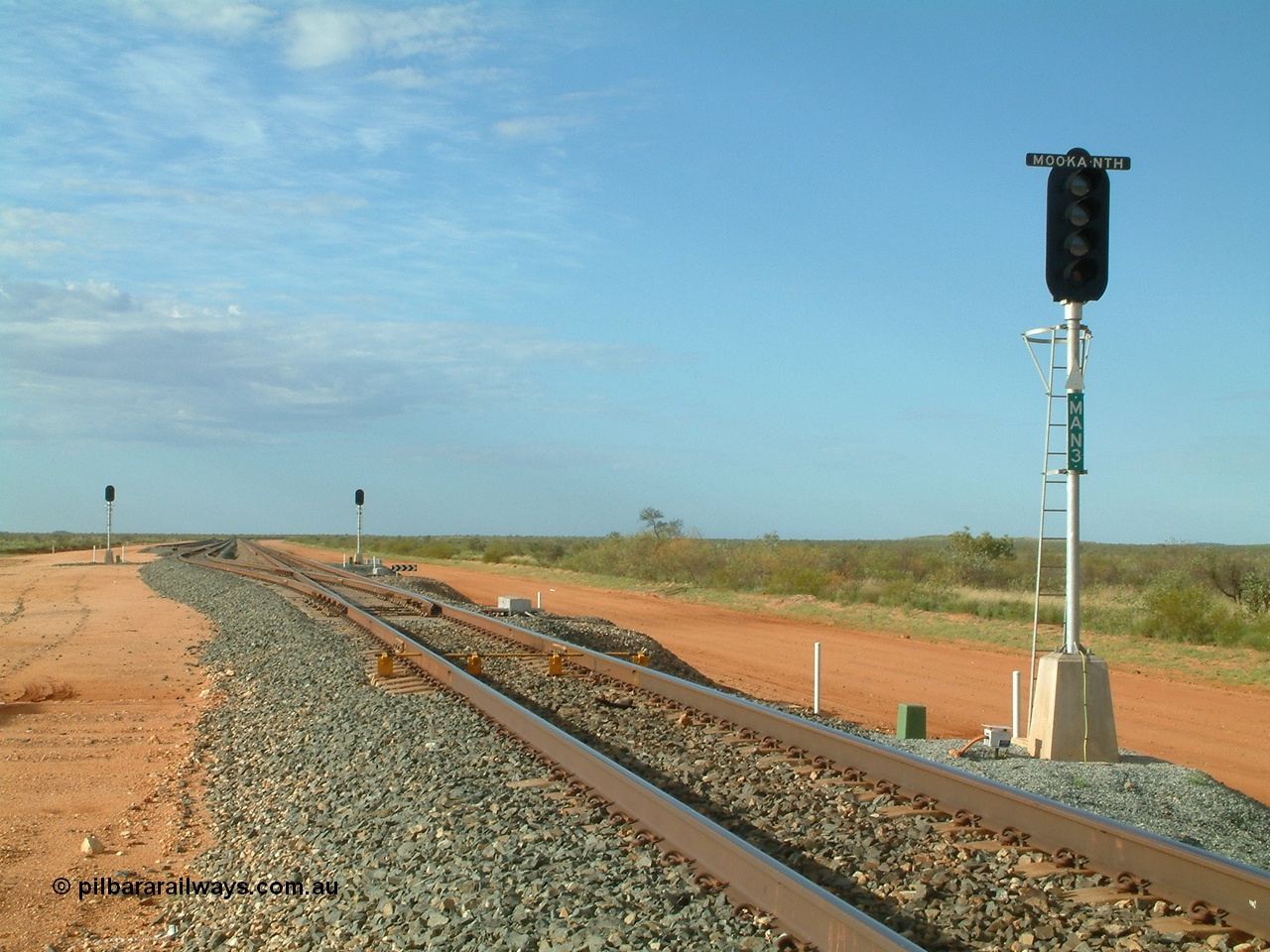 040407 075227
Mooka Siding, north end looking south past the arrival signal LED type MAN 3, DED 'dragging equipment detector' bars are visible before the turnout, passing track branching off to the left. 7th April 2004.
