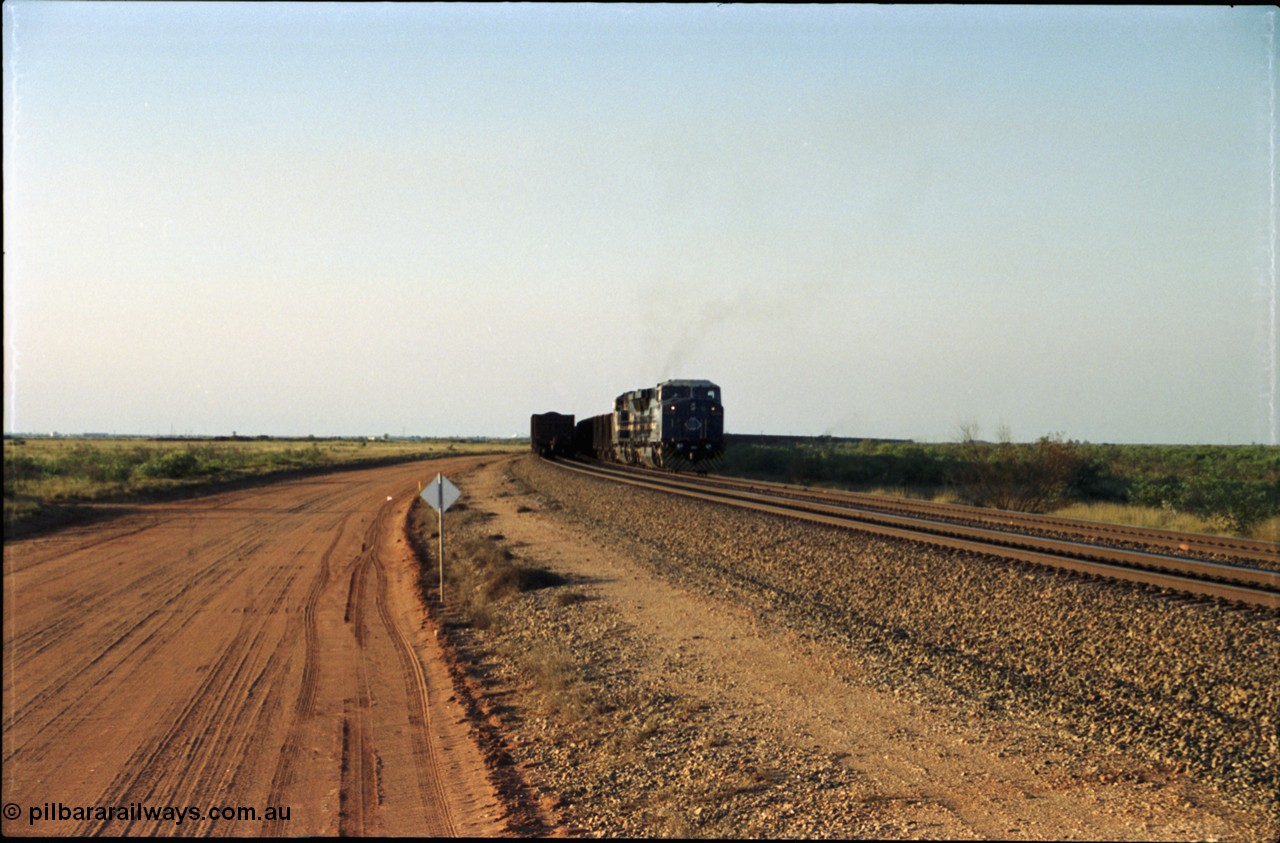 203-00
Bing Siding, an empty train behind BHP General Electric AC6000 unit 6076 'Mt Goldsworthy' serial 51068 runs around the passing track with a loaded train on the mainline.
