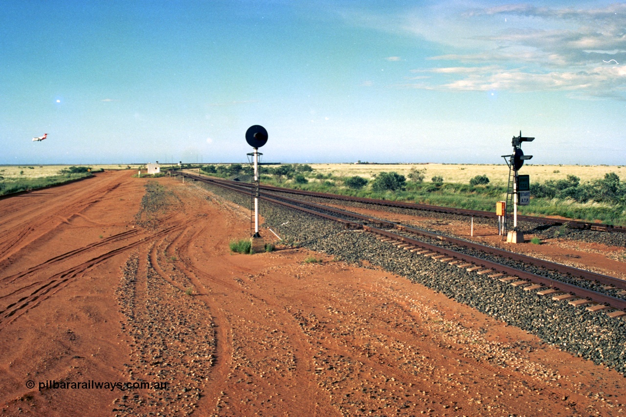220-27
Goldsworthy Junction, an empty train on the Newman line approaches having departed Nelson Point. The line merging in from the right is the Goldsworthy line to Yarrie and Nimingarra, which can then be made out diverging to the left just after the interlocking room in front of the train.
