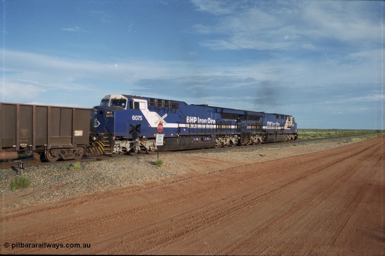 225-21
At the 24.1 km grade crossing on the BHP Newman line, the afternoon departure for Yandi mine heads south behind the standard double General Electric AC6000 units with GE Erie built 6075 serial 51067 second unit to lead sister unit 6074 with another AC6000 unit mid-train. This was before the units were named. [url=https://goo.gl/maps/qGkyfiuy6212]GeoData[/url].
Keywords: 6075;GE;AC6000;51067;
