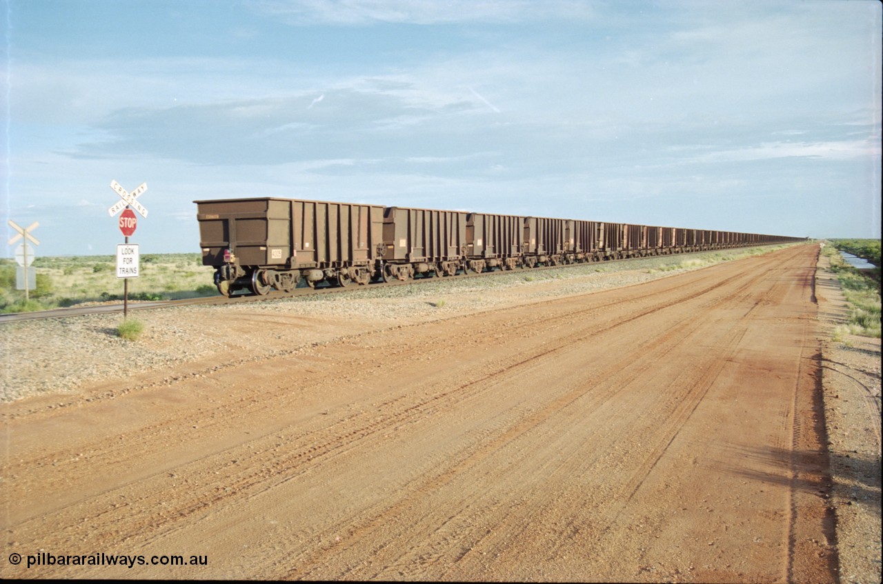 225-25
At the 24.1 km grade crossing on the BHP Newman line the end of the afternoon Yandi train is seen heading south with last waggon 4305, one of 126 such waggons constructed during 1997 out of 3CR12 stainless steel in an effort to eliminate painting and to reduce wear on the waggon body. This design was designated HC7081. [url=https://goo.gl/maps/qGkyfiuy6212]GeoData[/url].
Keywords: 4305;United-Goninan-WA;3CR12;HC7081;