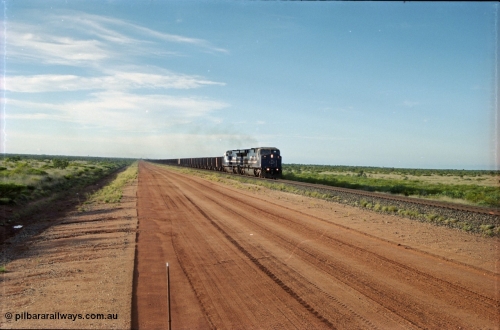 225-17
At the 24.1 km grade crossing on the BHP Newman line, the afternoon departure for Yandi mine heads south behind the standard double General Electric AC6000 units with GE Erie built 6074 serial 51066 leading sister unit 6075 with another AC6000 unit mid-train. This was before the units were named. [url=https://goo.gl/maps/qGkyfiuy6212]GeoData[/url].
Keywords: 6074;GE;AC6000CW;51066;