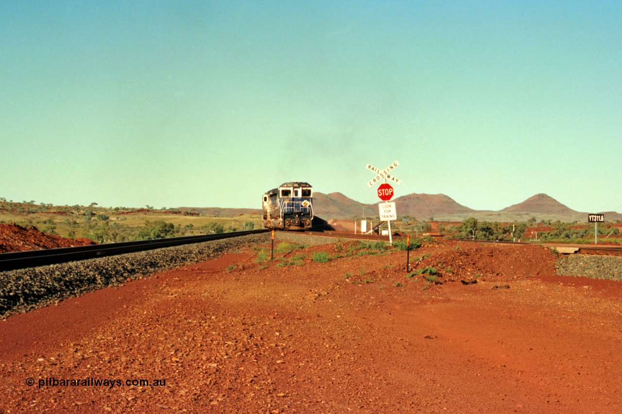 229-01
Yandi Two balloon switch looking east with the Three Sisters forming the background. Empty BHP train heading for the balloon loop for loading, grade crossing is the YT 311.5 km. [url=https://goo.gl/maps/DcycDGojcBt]GeoData[/url].
