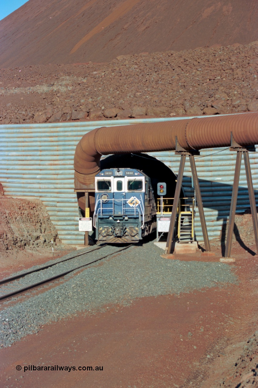 229-16
Yandi Two loadout, looking at the exit portal of the tunnel as Goninan rebuild CM40-8M GE unit 5650 'Yawata' serial 8412-07 / 93-141 drags a loading through at 1.2 km/h, the massive pile of ore is gravity fed into the waggons via two sets of hydraulic chutes, the red and amber lights control access through the tunnel and the steel pipe is for dust extraction. [url=https://goo.gl/maps/jmtnauf76Zq]GeoData[/url].
Keywords: 5650;Goninan;GE;CM40-8M;8412-07/93-141;rebuild;AE-Goodwin;ALCo;M636C;5481;G6061-2;