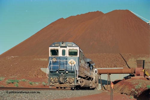 229-20
Yandi Two loadout, looking at the exit portal of the tunnel as Goninan rebuild CM40-8M GE unit 5650 'Yawata' serial 8412-07 / 93-141 drags a loading train through at 1.2 km/h, the massive pile of ore is gravity fed into the waggons via two sets of hydraulic chutes, the original pedestal radial stacker is visible above the ore along with the extraction fan. [url=https://goo.gl/maps/jmtnauf76Zq]GeoData[/url].
Keywords: 5650;Goninan;GE;CM40-8M;8412-07/93-141;rebuild;AE-Goodwin;ALCo;M636C;5481;G6061-2;