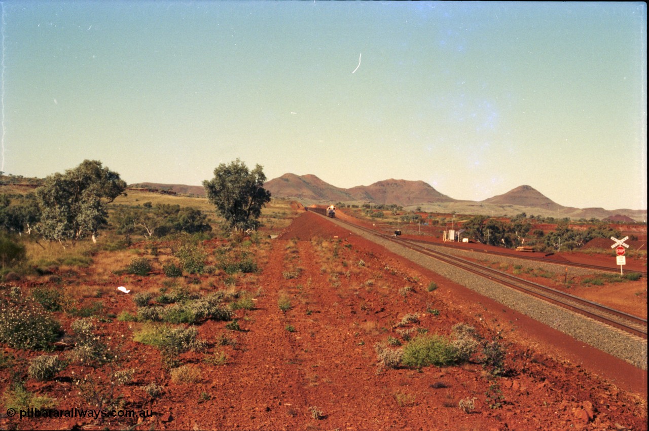 230-00
Yandi Two switch looking east with the Three Sisters forming the background. Empty BHP train heading for the balloon loop for loading, grade crossing is the YT 311.5 km. Geodata [url=https://goo.gl/maps/DcycDGojcBt] -22.713725, 119.055762 [/url].
