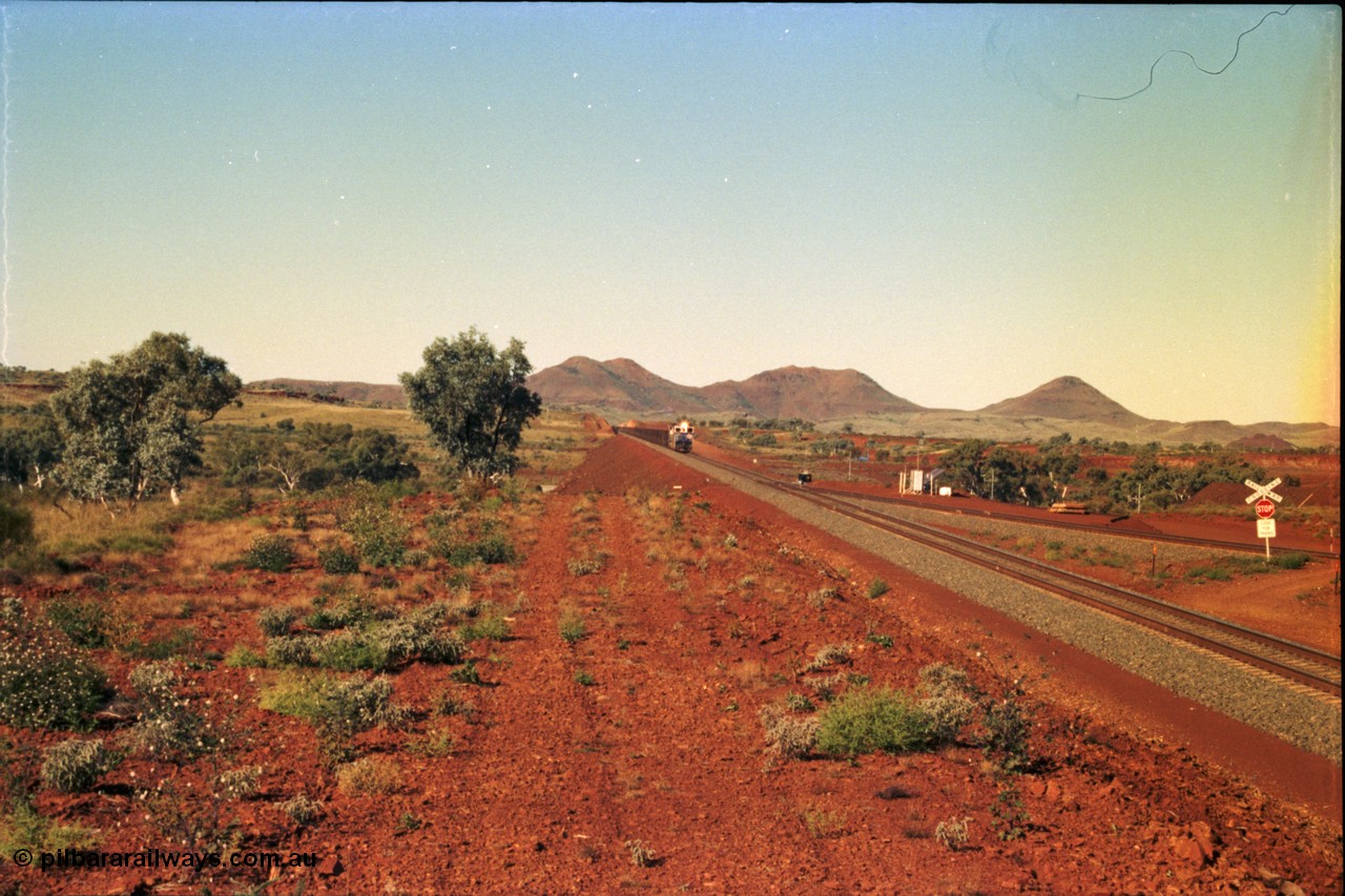 230-01
Yandi Two switch looking east with the Three Sisters forming the background. Empty BHP train heading for the balloon loop for loading, grade crossing is the YT 311.5 km. Geodata [url=https://goo.gl/maps/DcycDGojcBt] -22.713725, 119.055762 [/url].
