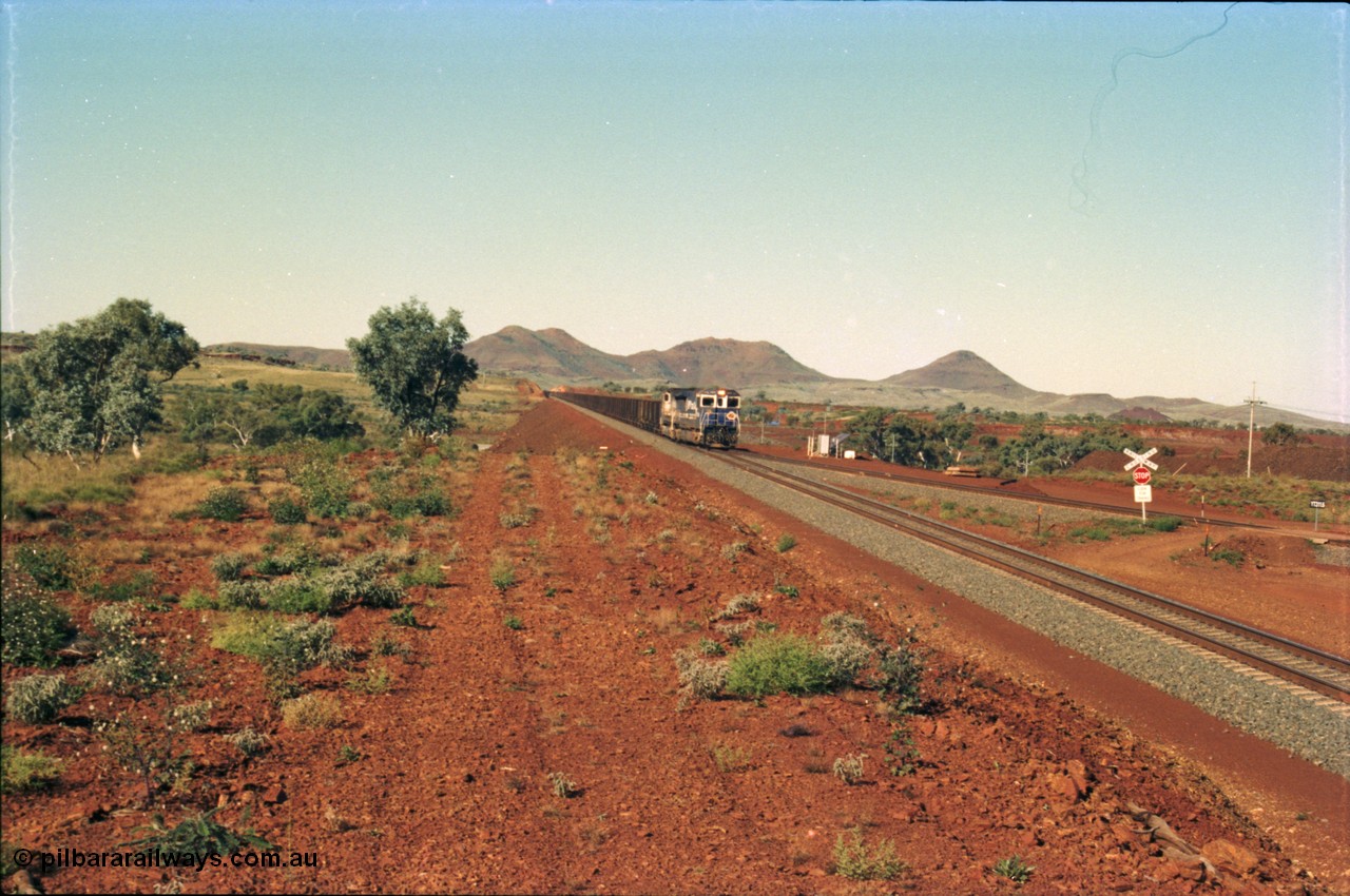 230-05
Yandi Two switch looking east with the Three Sisters forming the background. Empty BHP train heading for the balloon loop for loading, grade crossing is the YT 311.5 km. Geodata [url=https://goo.gl/maps/DcycDGojcBt] -22.713725, 119.055762 [/url].
