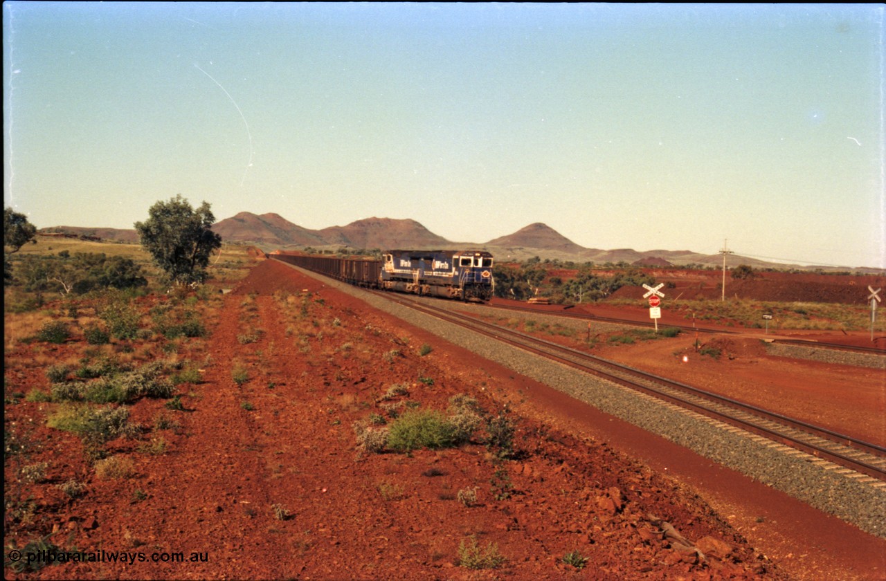 230-07
Yandi Two switch looking east with the Three Sisters forming the background. Empty BHP train with dual CM40-8M units on the point, heading for the balloon loop for loading, grade crossing is the YT 311.5 km. Geodata [url=https://goo.gl/maps/DcycDGojcBt] -22.713725, 119.055762 [/url].
