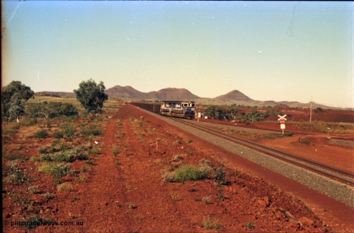 230-06
Yandi Two switch looking east with the Three Sisters forming the background. Empty BHP train heading for the balloon loop for loading, grade crossing is the YT 311.5 km. Geodata [url=https://goo.gl/maps/DcycDGojcBt] -22.713725, 119.055762 [/url].
