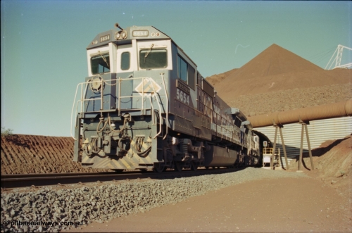 230-18
Yandi Two load-out tunnel exit side portal, Goninan rebuild GE CM40-8M model 5654 'Kashima' serial 8412-11/93-145 leads a loading train 1.2 km/h. The ore stockpile and pedestal stacker are visible. The livery is the marigold version of the BHP Australia logo. Geodata [url=https://goo.gl/maps/h68ia1caJvL2] -22.718338, 119.039909 [/url].
Keywords: 5654;Goninan;GE;CM40-8M;8412-11/93-145;rebuild;Comeng-NSW;ALCo;M636C;5493;C6084-9;