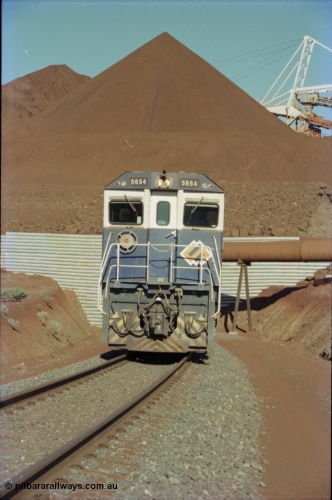 230-21
Yandi Two load-out tunnel exit side portal, Goninan rebuild GE CM40-8M model 5654 'Kashima' serial 8412-11/93-145 leads a loading train 1.2 km/h. The ore stockpile and pedestal stacker are visible. The livery is the marigold version of the BHP Australia logo. Geodata [url=https://goo.gl/maps/h68ia1caJvL2] -22.718338, 119.039909 [/url].
Keywords: 5654;Goninan;GE;CM40-8M;8412-11/93-145;rebuild;Comeng-NSW;ALCo;M636C;5493;C6084-9;