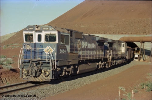 230-22
Yandi Two load-out tunnel exit side portal, Goninan rebuild GE CM40-8M model 5654 'Kashima' serial 8412-11/93-145 leads a loading train 1.2 km/h. The livery is the marigold version of the BHP Australia logo. Geodata [url=https://goo.gl/maps/h68ia1caJvL2] -22.718338, 119.039909 [/url].
Keywords: 5654;Goninan;GE;CM40-8M;8412-11/93-145;rebuild;Comeng-NSW;ALCo;M636C;5493;C6084-9;