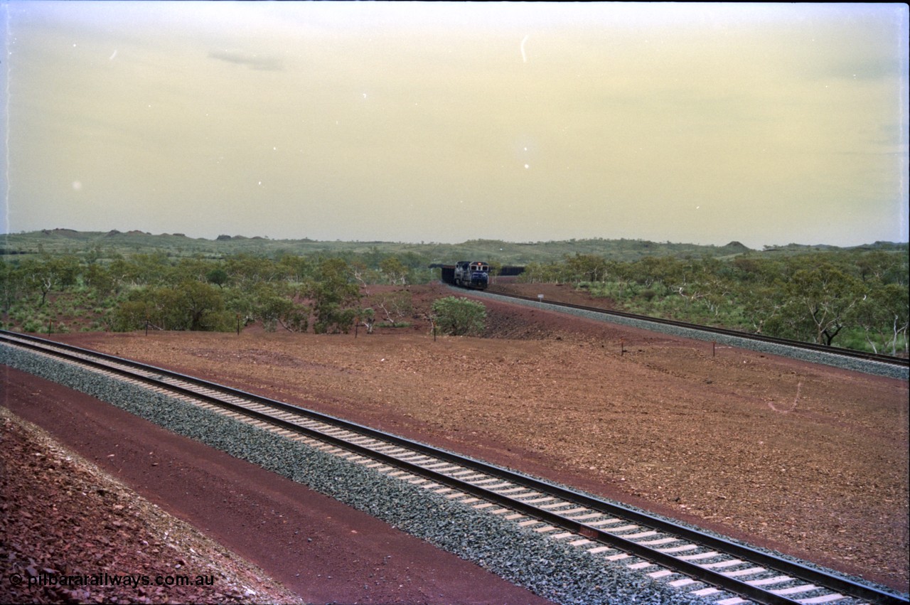 232-04
Yandi Two, view west from near the 311.6 km grade crossing, train can be seen loading on the right. [url=https://goo.gl/maps/3tst5WV949N2]GeoData[/url].
