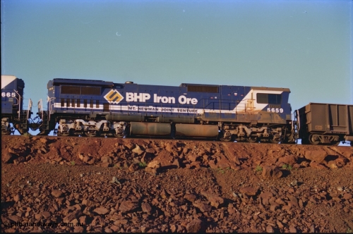 232-06
Yandi One balloon loop, mid-train remote units of train no. 1718 which is partway through loading, BHP Iron Ore unit 5659 'Kobe' serial 8412-04 / 94-150 leads cabless unit 5665, both are Goninan rebuild CM40-8M GE units, 59 is still in the teal and marigold logo livery. 3rd of February 1997. [url=https://goo.gl/maps/JhTwdFuTRZo]GeoData[/url].
Keywords: 5659;Goninan;GE;CM40-8M;8412-04/94-150;rebuild;AE-Goodwin;ALCo;M636C;5483;G6061-4;