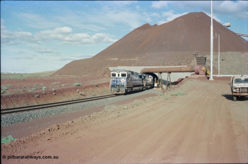 233-14
Yandi Two exit portal or loaded car side of load-out tunnel, the Yandi Two load-out has two load-out stations or vaults to allow to different products to be loaded. Only one vault is used at a time. A loading train lead by BHP Iron Ore's Goninan rebuild CM40-8M GE unit 5650 'Yawata' serial 8412-07 / 93-141 as it drags the train through at 1.2 km/h with assistance from two sister units. [url=https://goo.gl/maps/RgJfYGtPXb52]GeoData[/url].
Keywords: 5650;Goninan;GE;CM40-8M;8412-07/93-141;rebuild;AE-Goodwin;ALCo;M636C;5481;G6061-2;