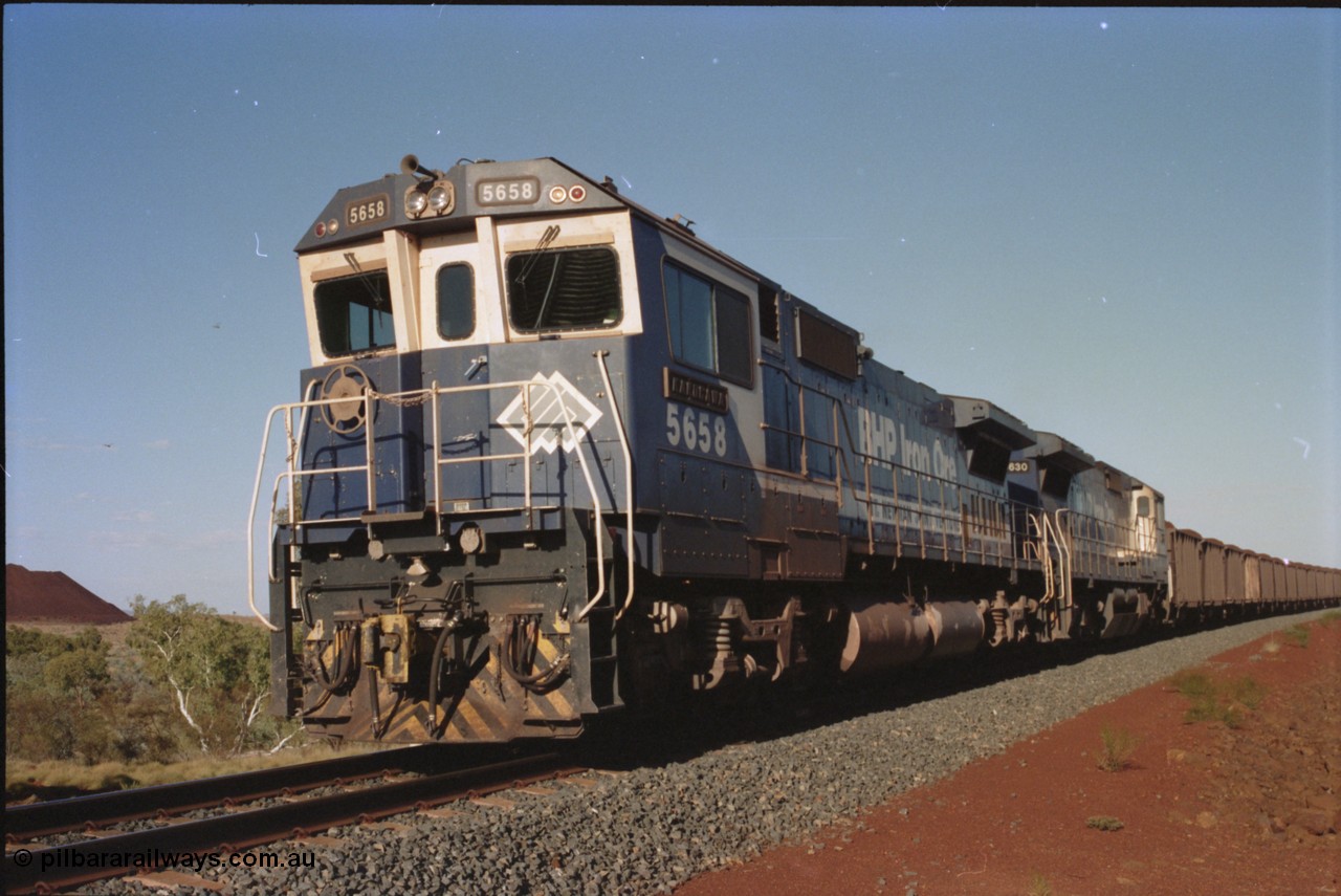 234-18
Yandi Two, BHP Iron Ore Goninan rebuild CM40-8M GE unit 5658 'Kakogawa' serial 8412-03 / 94-149 on the front of a 240 waggon loaded train, this configuration was trialled for a time with two Dash 8 locos, 120 waggons, Dash 8, 120 waggons and Dash 8. Circa 1998.
Keywords: 5658;Goninan;GE;CM40-8M;8412-03/94-149;rebuild;AE-Goodwin;ALCo;M636C;5480;G6061-1;