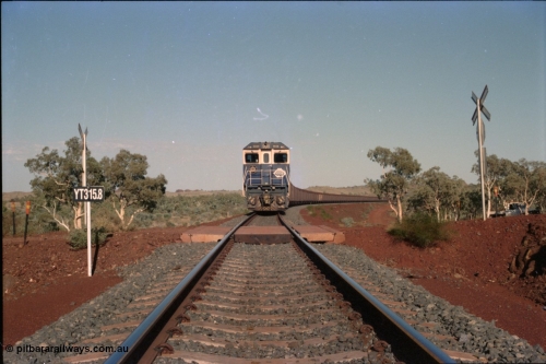 234-35
Yandi Two, BHP Iron Ore Goninan rebuild CM40-8M GE unit 5658 'Kakogawa' serial 8412-03 / 94-149 on the front of a 240 waggon loaded train, this configuration was trialled for a time with two Dash 8 locos, 120 waggons, Dash 8, 120 waggons and Dash 8. View looking across the YT315.8 km grade crossing and 5658 back to the ore stockpile at the loadout. Circa 1998.
Keywords: 5658;Goninan;GE;CM40-8M;8412-03/94-149;rebuild;AE-Goodwin;ALCo;M636C;5480;G6061-1;