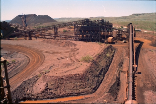 239-23
Overview of Yandi One OHP plant as viewed from the head end of CV2 conveyor which runs from the primary crusher to the reclaim pile. Visible from the left is the radial stacker on the stockpile, power station radiators, new and old side tertiary crushing structures, sub-station 4, the workshops in the background and on the secondary crusher structure. The reclaim tunnels and conveyor CV3 are visible running from the bottom of the image to the secondary crusher. [url=https://goo.gl/maps/EyA7dYyg3yK2]GeoData[/url].
