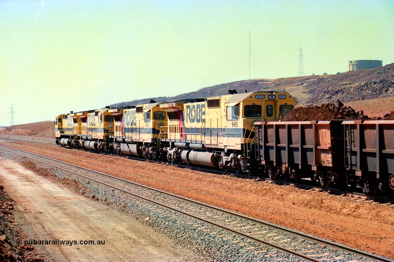 246-26
Cape Lambert, a Robe River loaded Deepdale train rolls along the mainline behind the standard quad Dash 8 power with 202 waggons with newly extended roads either side of it. 9425 which is a Goninan WA ALCo to GE rebuild CM40-8M with serial 6266-8 / 89-85 from August 1989 riding on Hi-Ad bogies and was originally an AE Goodwin built M636 ALCo serial C-6041-4 and built new for Mt Newman Mining (later BHP Iron Ore) in April 1970 and numbered 5468, sold to Robe and delivered by road 17th August 1982. Everything below the frame is ALCo while above is GE and Pilbara Cab. 22nd May 2002.
Keywords: 9425;Goninan;GE;CM40-8M;6266-8/89-85;rebuild;AE-Goodwin;ALCo;M636;G-6041-4;