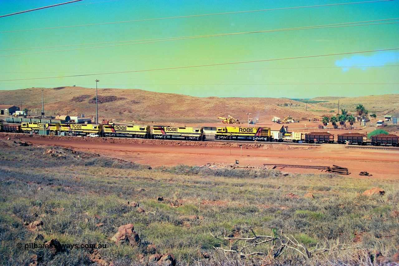 247-20
Cape Lambert yard view with Robe River Comeng WA ALCo Schenectady NY model rebuild C636R unit 9426 dragging a loaded 101 waggon rake from the South Yard across Bells Crossing while a brace of four Goninan CM40-8M GE rebuilds wait at the fuel point for a departure with an empty train. Approximate location of photo is [url=https://goo.gl/maps/TvJoLDjReJ2xoob69]here[/url]. 22nd May 2002.
Keywords: 9426;Comeng-WA;C636R;WA143-1;rebuild;ALCo;Schenectady-NY;C636;Conrail;6782;3499-3;