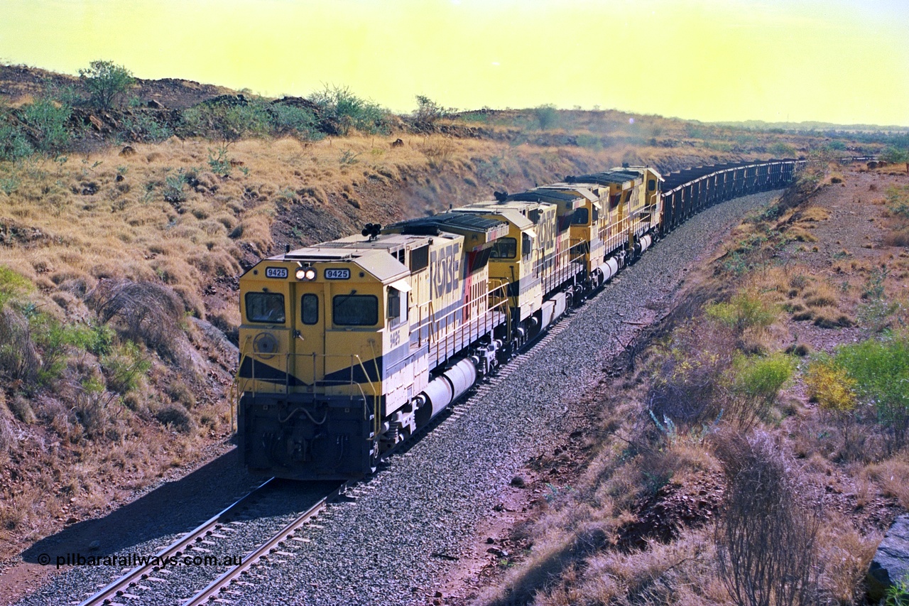247-32
Near Cooya Pooya at the 37.5 km on the Robe River Cape Lambert line an empty train is about to pass under the town water supply pipeline and pass through Lockyer Gap behind the standard Robe power of quad CM40-8M or Dash 8 locomotives led by 9425 which is a Goninan WA ALCo to GE rebuild CM40-8M with serial 6266-8 / 89-85 from August 1989 riding on Hi-Ad bogies and was originally an AE Goodwin built M636 ALCo serial C-6041-4 and built new for Mt Newman Mining (later BHP Iron Ore) in April 1970 and numbered 5468, sold to Robe and delivered by road 17th August 1982. Location is [url=https://goo.gl/maps/nLyndU6bg2HA5SZX6]here[/url].22nd May 2002.
Keywords: 9425;Goninan;GE;CM40-8M;6266-8/89-85;rebuild;AE-Goodwin;ALCo;M636;G-6041-4;