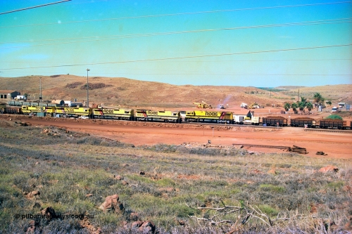 247-21
Cape Lambert yard view with Robe River Comeng WA ALCo Schenectady NY model rebuild C636R unit 9426 dragging a loaded 101 waggon rake from the South Yard across Bells Crossing while a brace of four Goninan CM40-8M GE rebuilds wait at the fuel point for a departure with an empty train. Approximate location of photo is [url=https://goo.gl/maps/TvJoLDjReJ2xoob69]here[/url]. 22nd May 2002.
Keywords: 9426;Comeng-WA;C636R;WA143-1;rebuild;ALCo;Schenectady-NY;C636;Conrail;6782;3499-3;