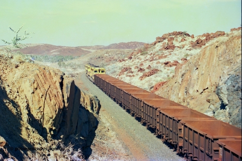 247-36
Near Cooya Pooya at the 37.5 km on the Robe River Cape Lambert line an empty train passes under the town water supply pipeline and pass through Lockyer Gap behind the standard Robe power of quad CM40-8M or Dash 8 locomotives led by 9425 with 9410, 9420 and last unit 9414 which is a Goninan WA ALCo to GE rebuild CM40-8M with serial 8206-11 / 91-124 from November 1991 riding on Dofasco bogies and was originally an AE Goodwin built M636 ALCo built new for Robe in December 1971 and numbered 262.005, later numbered 1714. Location is [url=https://goo.gl/maps/nLyndU6bg2HA5SZX6]here[/url].22nd May 2002.

