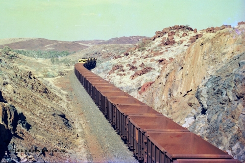 247-37
Near Cooya Pooya at the 37.5 km on the Robe River Cape Lambert line an empty train passes under the town water supply pipeline and pass through Lockyer Gap behind the standard Robe power of quad CM40-8M or Dash 8 locomotives led by 9425 with 9410, 9420 and last unit 9414 which is a Goninan WA ALCo to GE rebuild CM40-8M with serial 8206-11 / 91-124 from November 1991 riding on Dofasco bogies and was originally an AE Goodwin built M636 ALCo built new for Robe in December 1971 and numbered 262.005, later numbered 1714. Location is [url=https://goo.gl/maps/nLyndU6bg2HA5SZX6]here[/url].22nd May 2002.
